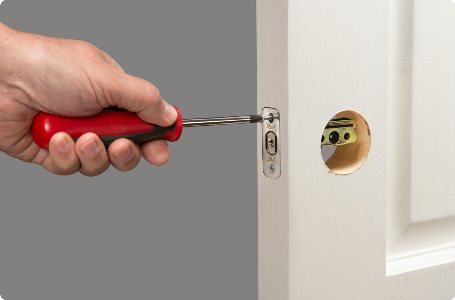 Man unscrewing a bolt on a front door